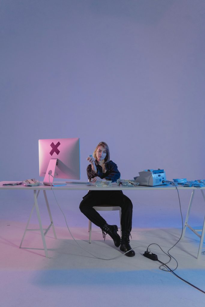 Compare our top 10 VPNs. This image features a lady at a desk surrounded by tech. 